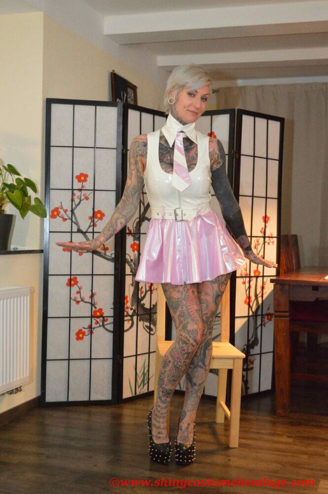 Tattooed platinum blonde Miss Francine models a raincoat over a latex dress - #14