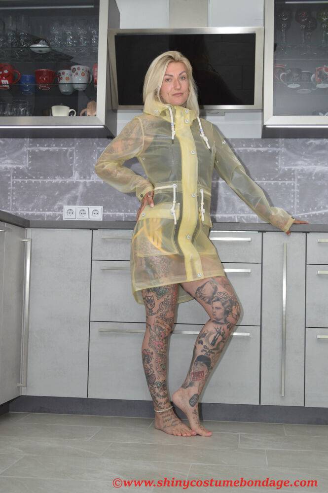 Tattooed blonde Miss Francine models barefoot in a raincoat over rubber wear - #16