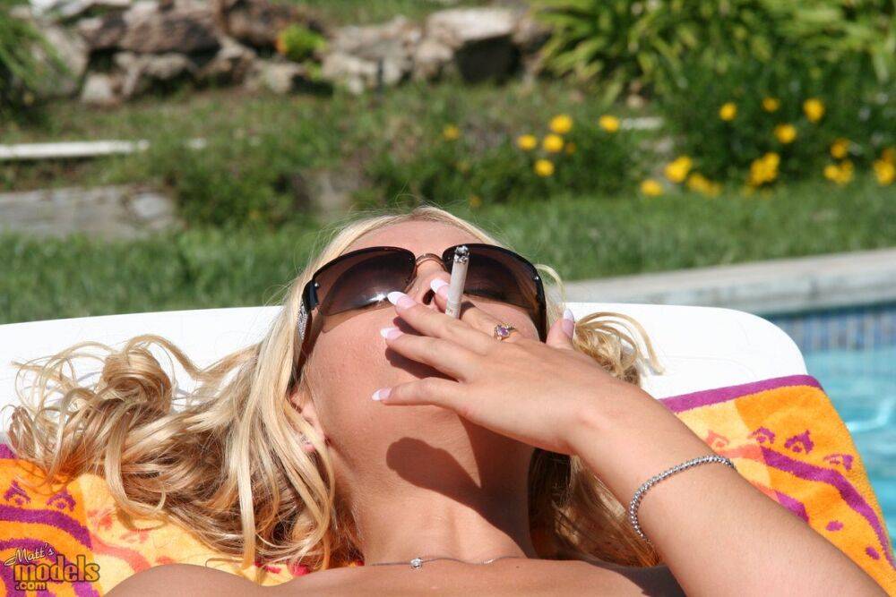 Blonde chick shows her bald pussy while smoking during nude sunbathing - #4