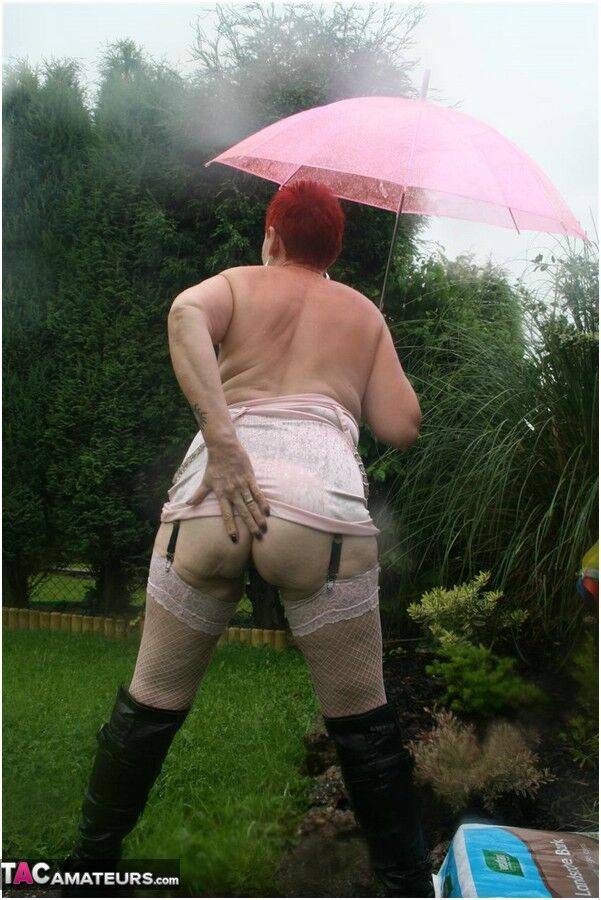 Older redhead Valgasmic Exposed models nude in the rain while holding a brolly - #12