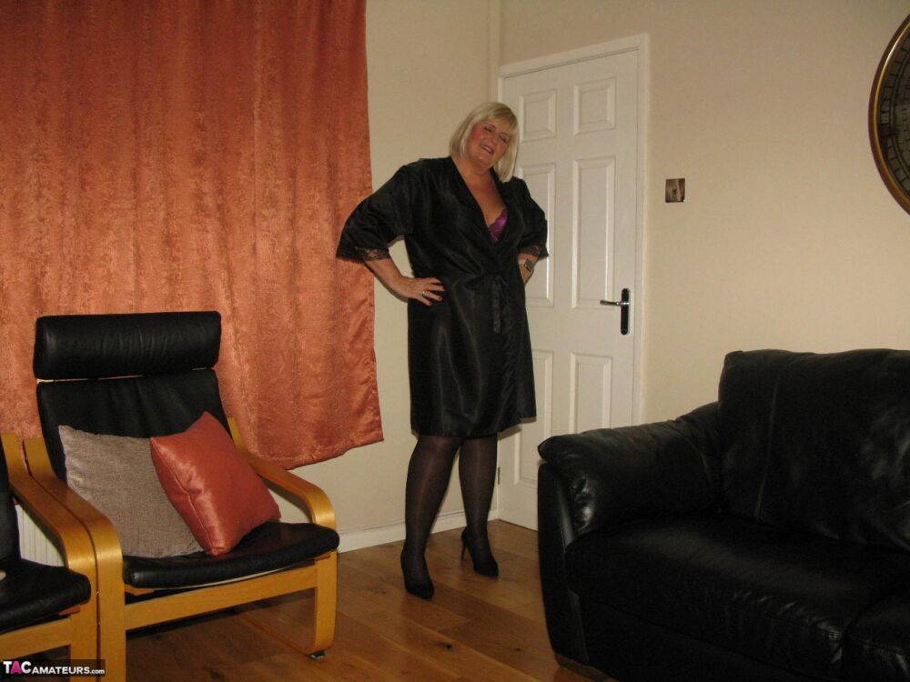 Older blonde BBW Chrissy Uk models lingerie & pantyhose on a leather loveseat - #4