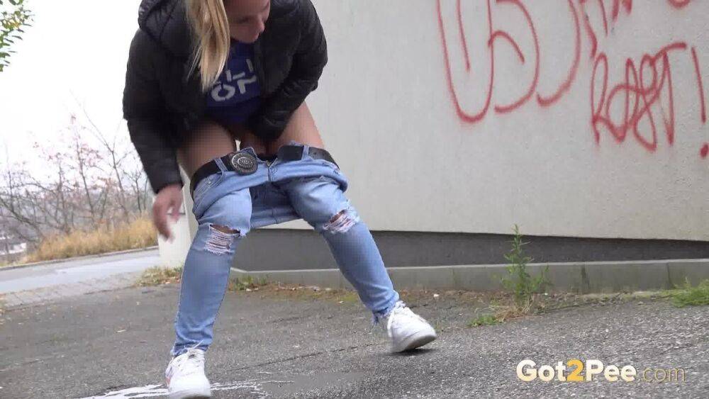 Czechoslovakian female Naomi Bennet takes a pee on pavement beside a building - #4