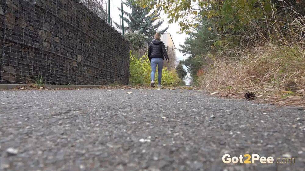 Czechoslovakian female Naomi Bennet takes a pee on pavement beside a building - #2