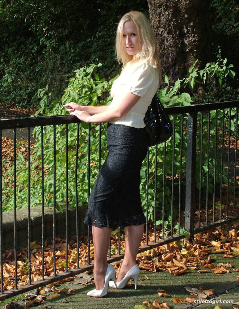 Clothed blonde Iona shows off her white stilettos in a long skirt by a park - #13