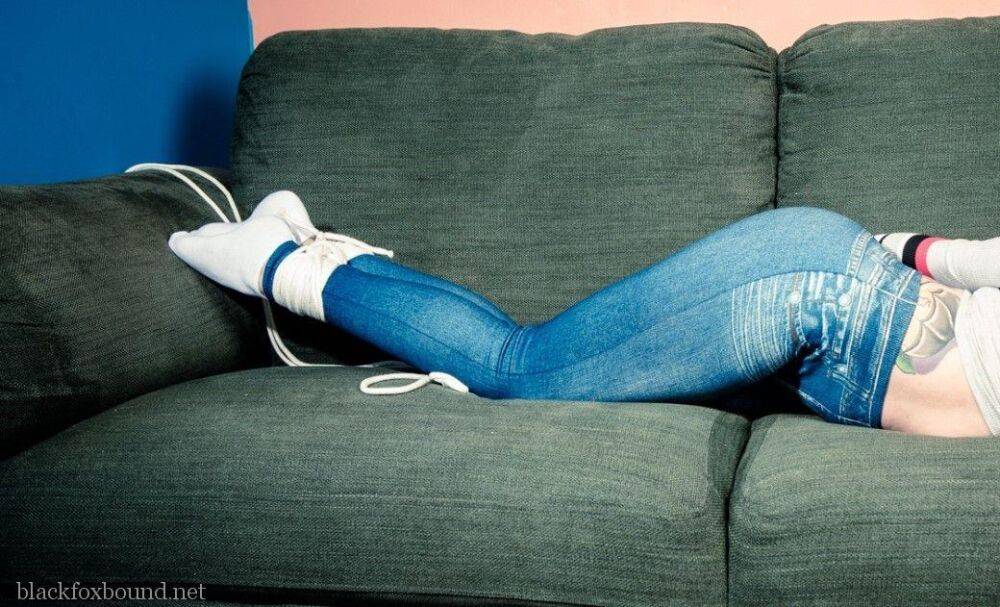 Dark haired chick is hogtied on a couch while closed in jeans and white socks - #9