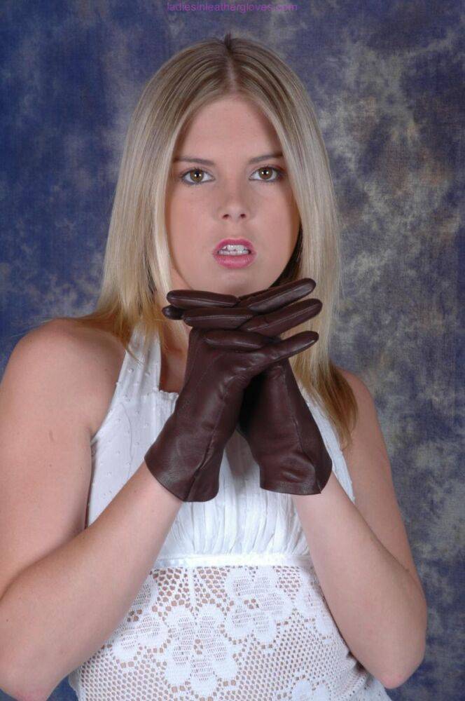 Blonde female pulls on brown leather gloves while wearing a white dress - #10