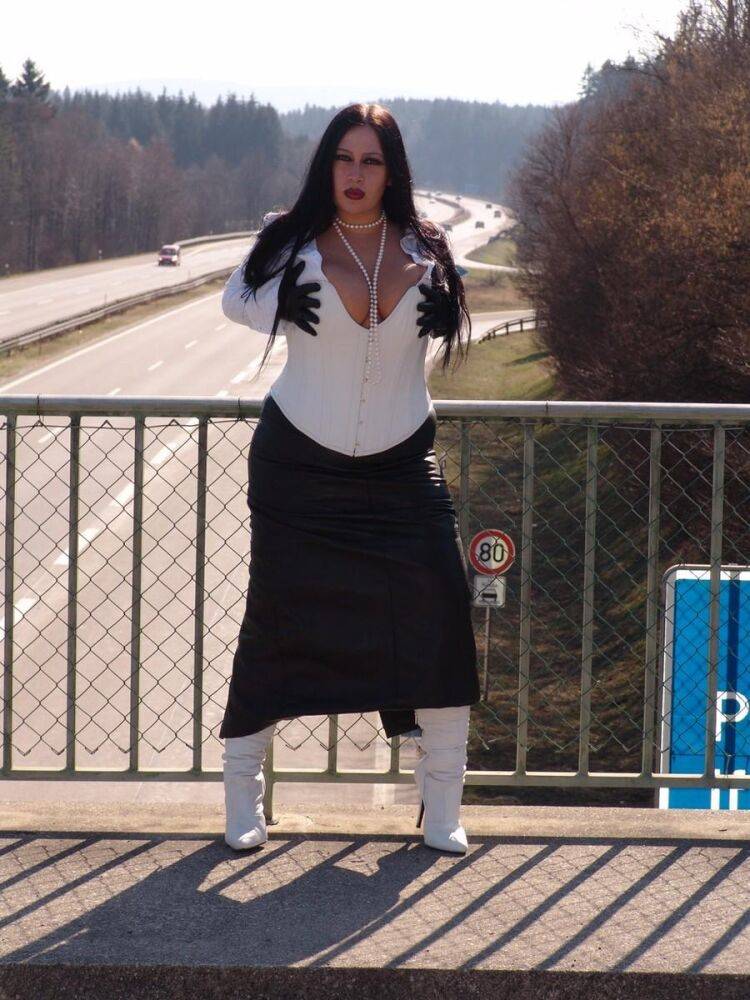 Goth model Lady Angelina poses in white latex wear & a black skirt on a bridge - #10