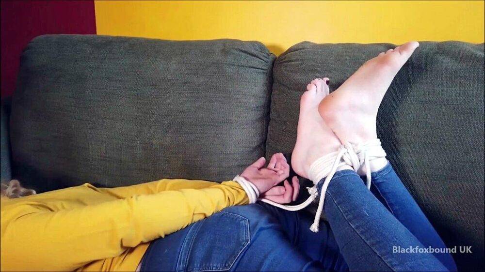 Barefoot white girl is hogtied on a sofa while ball gagged in her clothing - #2