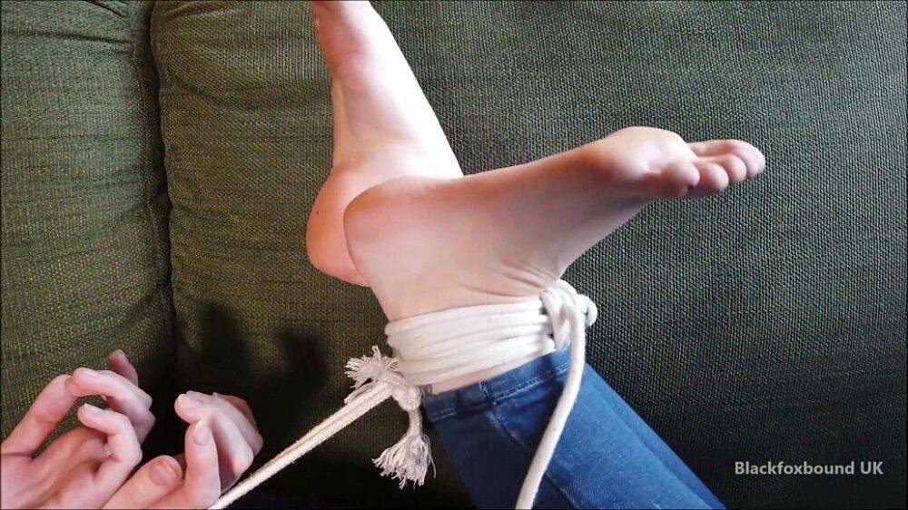 Barefoot white girl is hogtied on a sofa while ball gagged in her clothing - #11