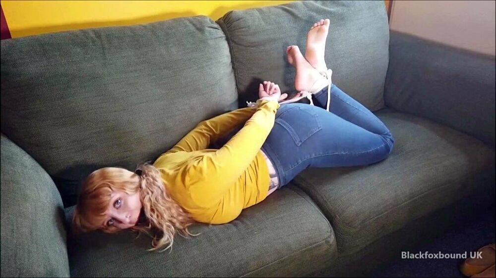 Barefoot white girl is hogtied on a sofa while ball gagged in her clothing - #10