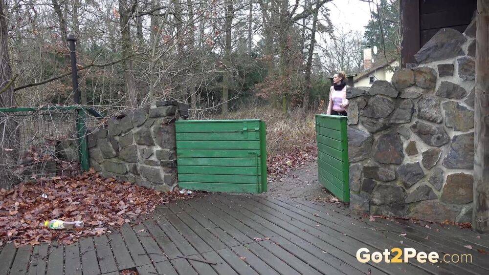 White girl Cynthia Vellons takes a piss on a deck behind a stone structure - #12