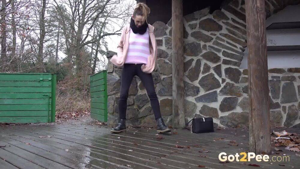 White girl Cynthia Vellons takes a piss on a deck behind a stone structure - #11