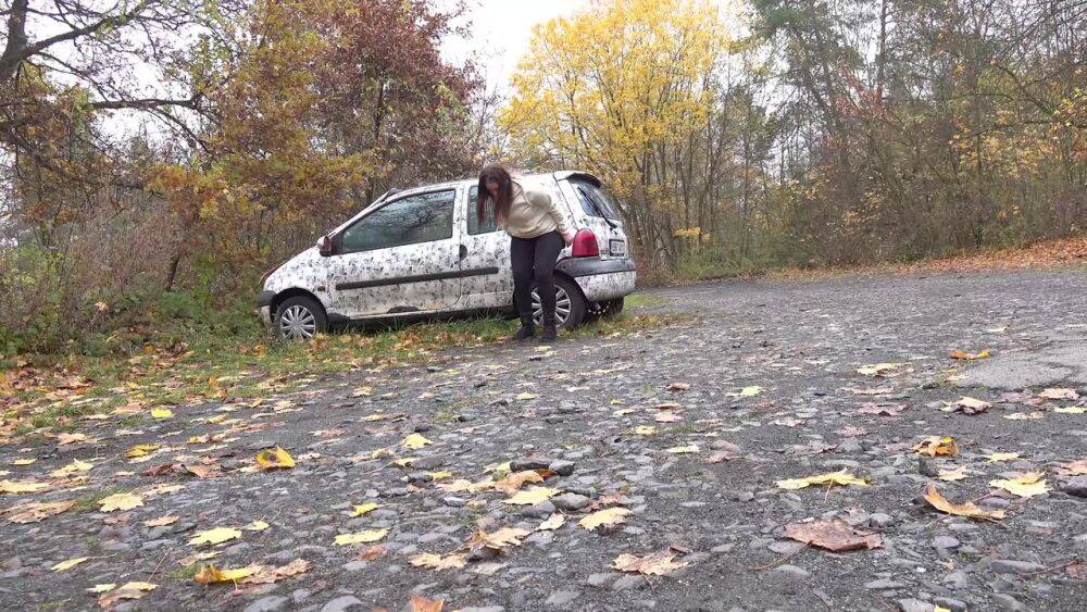 White girl Nicolette Noir takes a piss beside a parked car in a wooded setting - #10