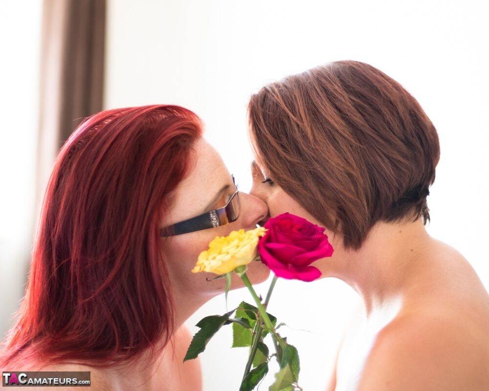 Middle-aged lesbians share a tender kiss while holding flowers - #14