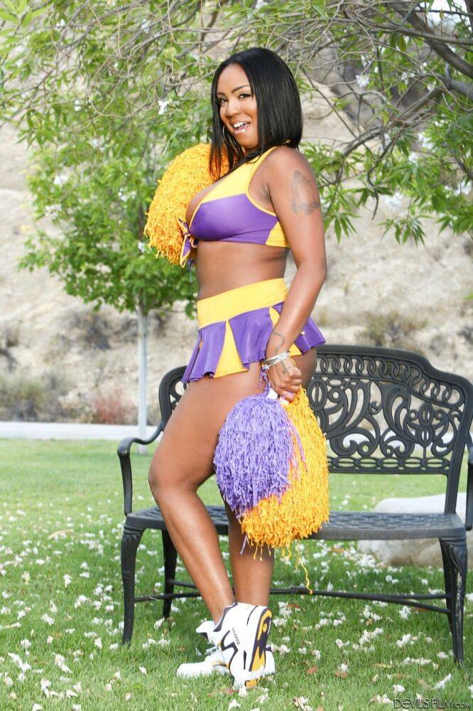 Phat cheerleader Layton Benton showing off her big natural pom poms in garden - #1