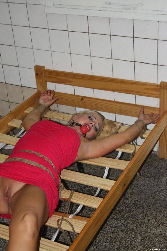 Ball gagged blond female struggles against rope restraints with dress hiked up - #15