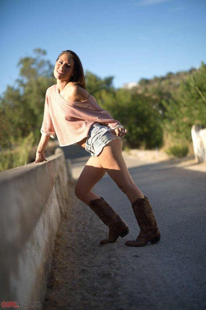 Solo model Jess West walks along a road in nothing more than her cowgirl boots - #12