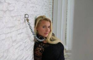 Fully clothed blonde is fastened to a wall with chains in handcuffs on nudesceleb.com