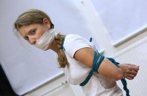 Clothed woman sports a pigtail while being gagged and tied up with rope on nudesceleb.com