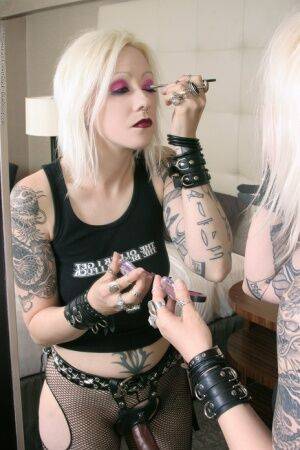 Tattooed blonde rocker Cindy B does her makeup while wearing a strapon cock on nudesceleb.com