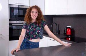 Teen solo girl Foxy Lee sports curly red hair while getting naked in a kitchen on nudesceleb.com