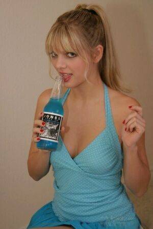 Young blonde Jana Jordan covers up her naked breasts while drinking blue soda - Jordan on nudesceleb.com