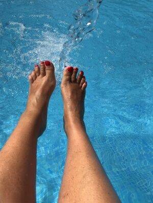 Mature woman Sweet Susi dips her painted toenails into a swimming pool on nudesceleb.com