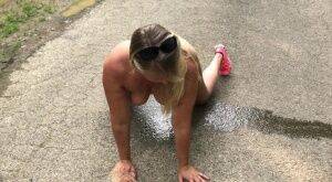 Blonde amateur Sweet Susi takes a piss while naked on a paved road on nudesceleb.com
