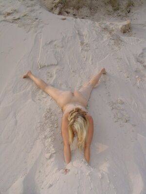 Blonde amateur Sweet Susi gets totally naked on a sandy bank by herself on nudesceleb.com