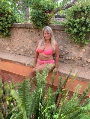 Older blonde Sweet Susi removes a pink bra and panty set to go nude in garden on nudesceleb.com