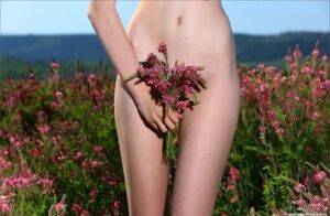 Skinny teen girl spreading naked pussy in a field while picking flowers on nudesceleb.com