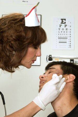 Mature nurse Elle Denay swaps oral with a young boy after cleaning his wounds on nudesceleb.com