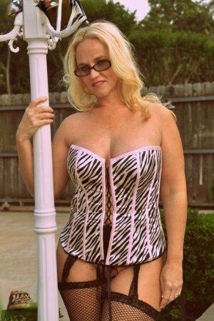 Blonde BBW Dee Siren shows her big ass in a hosiery and a corset while outside on nudesceleb.com