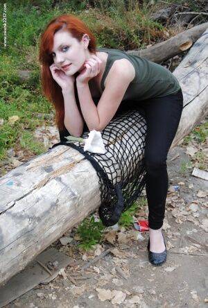 Young redhead chick Nicci Vice showing off tits and ass in the woods on nudesceleb.com