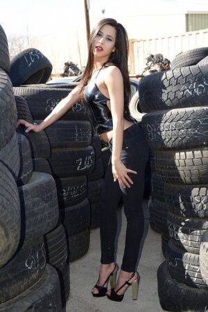 Latina amateur Bella Quinn covers her naked tits with hands amid tire stacks on nudesceleb.com