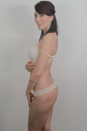 Tattooed milf Zoe Holloway showing off in a white lingerie and panties on nudesceleb.com