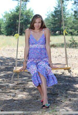 Long legged teen Mirabella doffs a dress to pose nude on a swing under a tree on nudesceleb.com