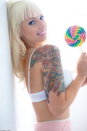 Tattooed blonde Lynn Pops strikes great poses with a lollipop in hand on nudesceleb.com