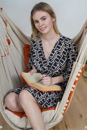 Blonde teen Ruth disrobes for a nude solo gig on an indoor hammock on nudesceleb.com