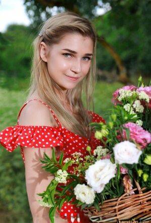 Young blonde Christine Cardo gets naked in a hilly field while picking flowers on nudesceleb.com