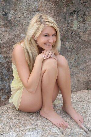 Young blonde Ashlee proudly shows her smooth pussy on a rock inside a park on nudesceleb.com