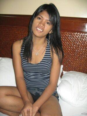 Cute Filipina girl strips to a black strapless bra and thong on a bed on nudesceleb.com