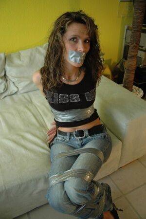 Clothed female is silenced and restrained with duct tape on a sofa on nudesceleb.com