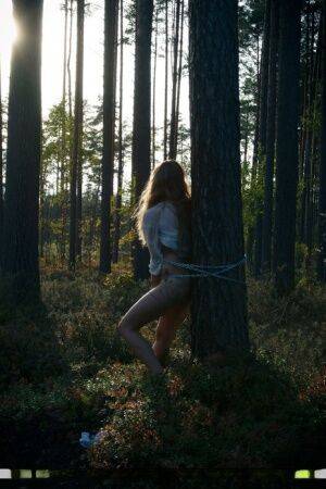 Handcuffed teen Kristine masturbates while being chained to a tree in woods on nudesceleb.com
