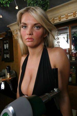 Blonde chick Ines Cudna exposes a large breast while tending bar on nudesceleb.com