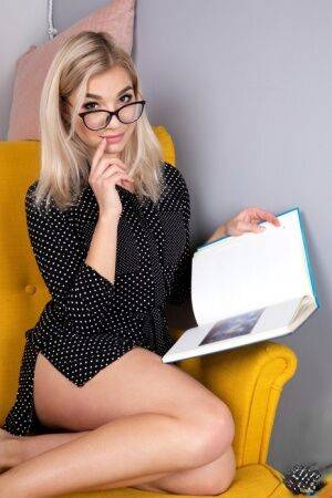 Geeky blonde Amelia undresses on a chair before playing with her shaved pussy on nudesceleb.com