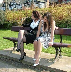 Clothed females admire each other high heeled shoes on a park bench on nudesceleb.com