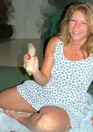 Mature amateur woman Devlynn toys her pussy with a veggie atop a sheet on nudesceleb.com