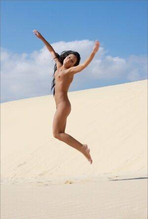 Totally naked brunette models by herself on a sand dune on nudesceleb.com