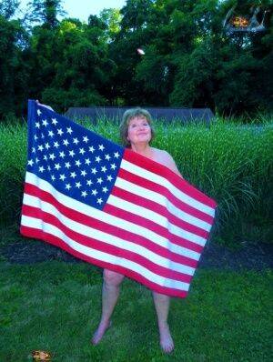 Older plumper Busty Bliss holds an American flag while totally naked in a yard - Usa on nudesceleb.com